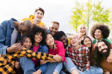 group of multiracial friends having picnic having fun in city park at sunset.
