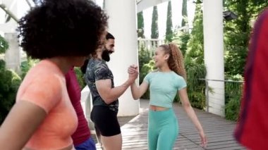 young athletes greeting each other, group of multiracial young friends meeting to play sports together, focus on Hispanic woman