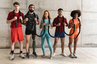 sporty multiracial young friends, in sportswear, with battle ropes and training outdoors