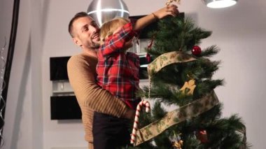Mutlu Kafkas babası oğlunu omuzlarında taşıyor ve Noel ağacının tepesine bir yıldız koymasına yardım ediyor. Noel partisi konsepti.