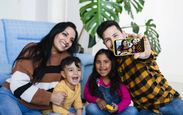 Family making a video call on a smart phone at home, Hispanic people, selfie.