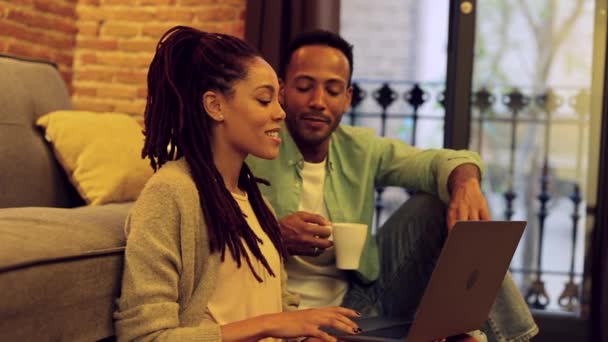 幸せな若い黒人男性と女性がアパートの床に座って オンラインで映画を見たり 休暇を計画したり スペースをコピーしたり — ストック動画
