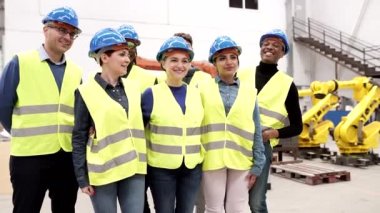 Mavi kasklı ve floresan yelekli çok ırklı insanlardan oluşan bir grup ayakta dikilip izledikleri endüstriyel makineler hakkında konuşuyorlar - kadınlara odaklan -