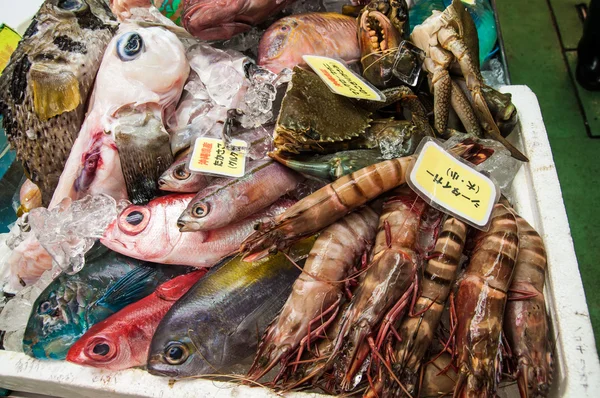 Låda med rå fisk och skaldjur som säljer på japanska marknaden Stockbild