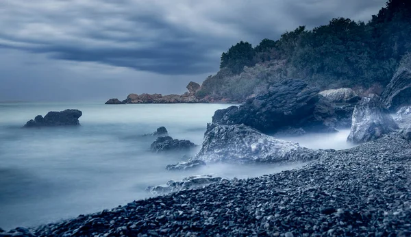 Panoramic seascape. Water rolling over rocks at coastline mist long exposure scenic background.