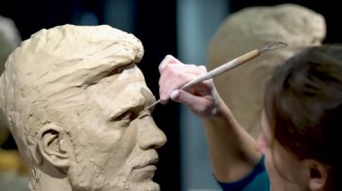 Kadın heykeltraş, insan kafası heykeli üzerinde çalışıyor..