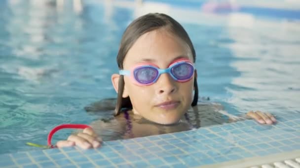 Šťastné děti v bazénu. Sportovní životní styl. Dívka v hodinách plavání — Stock video