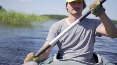 Gölde kayak yapan genç ve güzel bir adam. Nehirde kanoyla kürek çeken bir çocuk. Spor yürüyüşü, su raftingi.