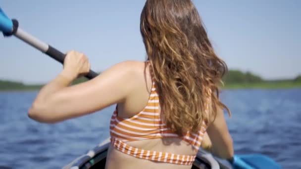 Gölde kayak yapan güzel bir genç kadın. Nehirde kanoyla kürek çeken bir kız. Spor yürüyüşü, su raftingi. — Stok video