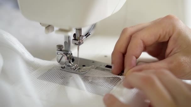 De man naait aan een naaimachine. Ontwerper zit en naait. Kleermaker werkt aan de naaimachine. Concept van de kledingproductie — Stockvideo