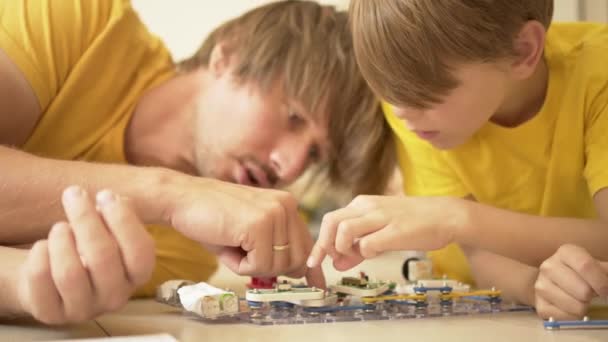 父は息子と遊ぶ。家族は一緒に時間を過ごす。親を持つ家庭でのロボット教室. — ストック動画