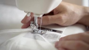 Adam dikiş makinesinde dikiş dikiyor. Tasarımcı oturuyor ve dikiş dikiyor. Dikiş makinesinde çalışan bir terzi. Giysi üretimi kavramı