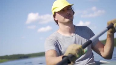 Gölde kayak yapan genç ve güzel bir adam. Nehirde kanoyla kürek çeken bir çocuk. Spor yürüyüşü, su raftingi.