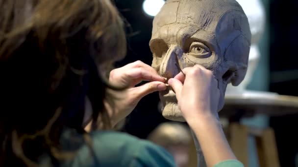 Woman sculptor at work on a sculpture of a human head. — Stock Video