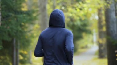 Genç adam sonbahar parkında koşar. Koşucu atletizmle meşgul. Spor yaşam tarzı konsepti. Sporcunun arka planı