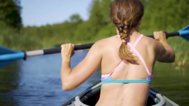 Beautiful young woman kayaking on lake. Girl rowing oars on a kayak on the river. Sports hike, water rafting in nature — Stock Video