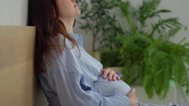 Une jolie femme enceinte s'assoit au lit. Le concept d'une grossesse heureuse. 9 mois d'attente pour un bébé. — Video