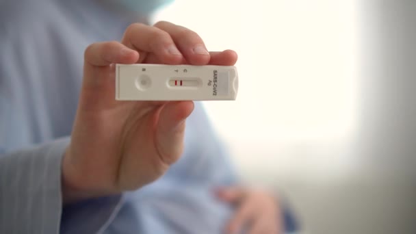 Gravid kvinna gör test. Närbild av fingrar som håller expressantigen covid test, positivt resultat — Stockvideo