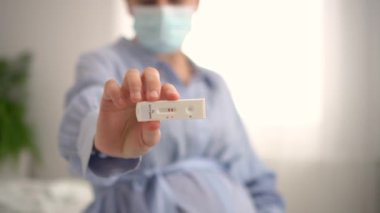 Hamile kadın test yapıyor. Ekspres antijen covid testi sonucu pozitif olan parmakları kapat