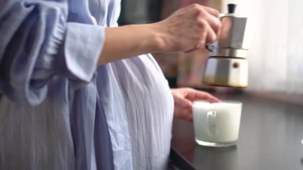 Egy aranyos terhes nő kávét tölt a kávéskannából. A boldog terhesség fogalma. Nem egészséges italok — Stock videók