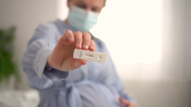 Hamile kadın test yapıyor. Ekspres antijen covid testi sonucu pozitif olan parmakları kapat