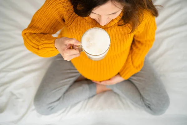 Nette schwangere Frau hält eine Tasse Kaffee in der Hand. Konzept einer glücklichen Schwangerschaft. Keine gesunden Getränke — Stockfoto