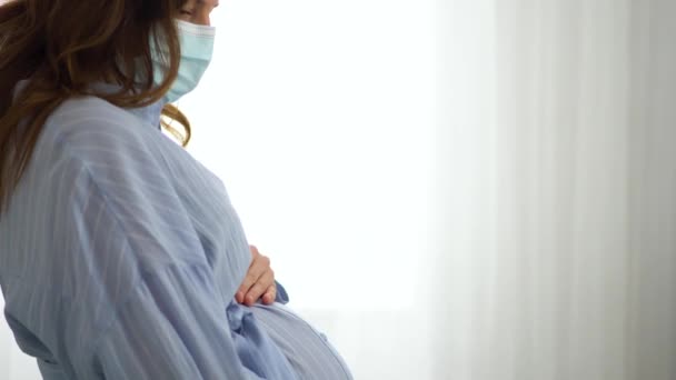 Беременная женщина носит медицинскую маску, чтобы защитить от вирусной инфекции. Медицинское обслуживание во время беременности — стоковое видео