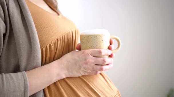 Aranyos terhes nő kezében egy csésze kávét. A boldog terhesség koncepciója. Nem egészséges italok — Stock videók