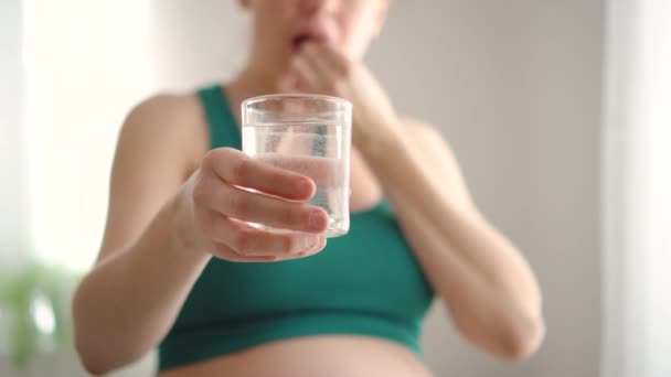 Těhotná žena drží v ruce sklenici vody a pilulku. Užívání vitamínů během těhotenství — Stock video
