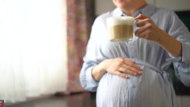 Aranyos terhes nő kezében egy csésze kávét. A boldog terhesség koncepciója. Nem egészséges italok — Stock videók