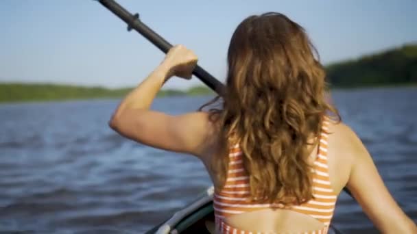 Beautiful young woman kayaking on lake. Girl rowing oars on a kayak on the river. Sports hike, water rafting in nature — Stock Video