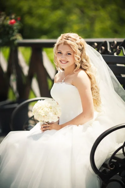 Young attractive bride sitting with bouquet — Stock Photo, Image