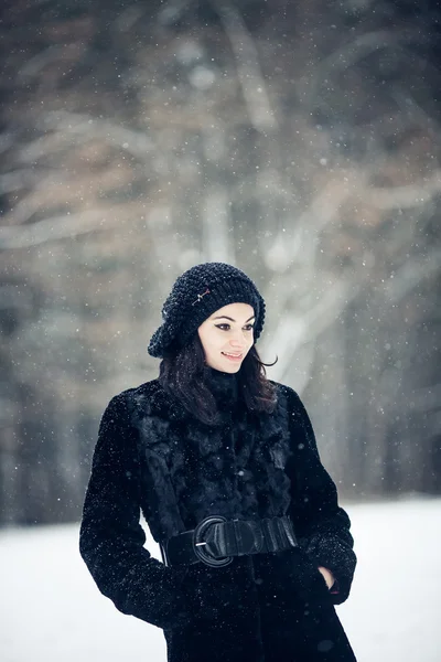 Schönes Mädchen, das in einem verschneiten Wald steht — Stockfoto