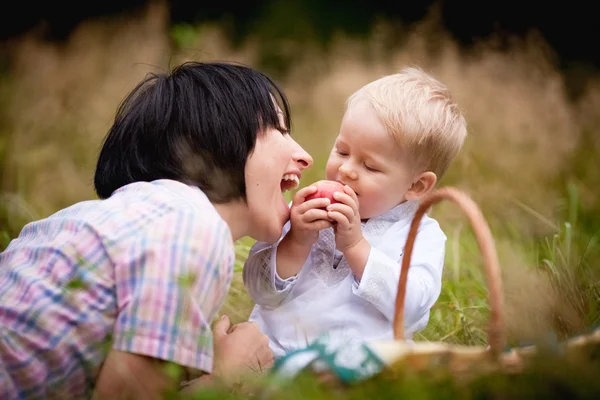 ママと息子の枝編み細工品バスケットと果物を食べて — ストック写真