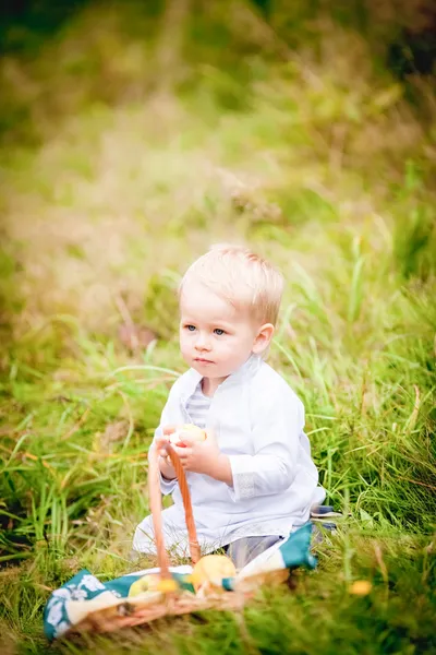 Kleiner Junge mit Korb und frisst ihn mit Früchten — Stockfoto