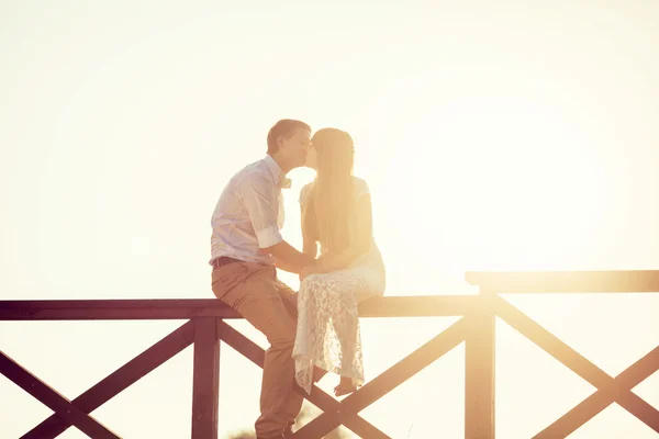 Recém-casados se beijam no portão ao sol — Fotografia de Stock