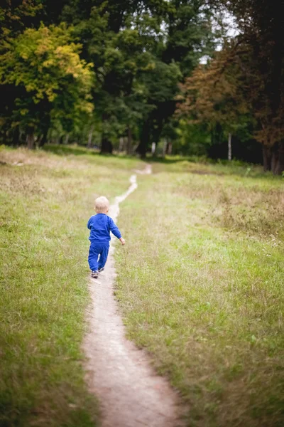 Little boy in a tracksuit flees into the forest — Stock Photo, Image