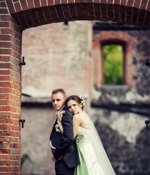 Hochzeit. Braut und Bräutigam umarmen sich vor der Kulisse eines alten Gebäudes — Stockfoto