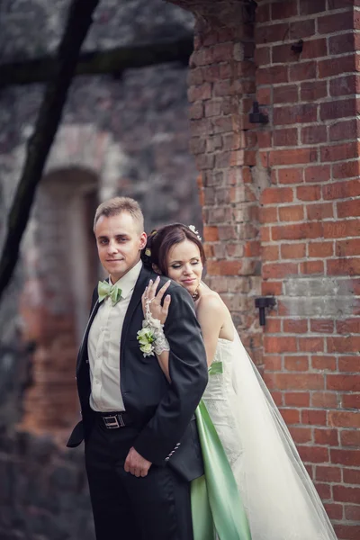 Hochzeit. Braut und Bräutigam umarmen sich vor der Kulisse eines alten Gebäudes — Stockfoto