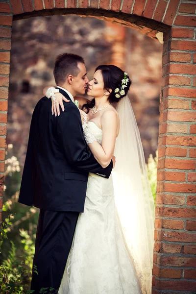 Hochzeit. Braut und Bräutigam umarmen sich vor der Kulisse eines alten Gebäudes — Stockfoto