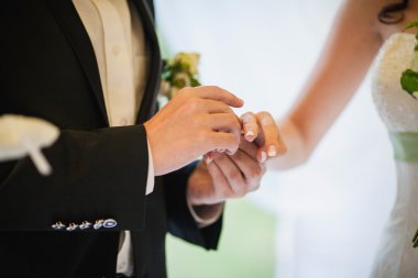 Damadın eli gelinin parmağına alyans takıyor.