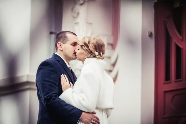 Свадьба. молодожёны целуются на фоне красивого здания — стоковое фото