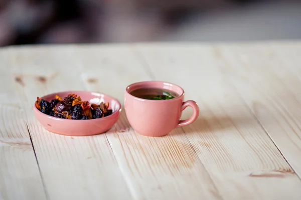 Kopje thee met aromatische droge thee op houten achtergrond — Stockfoto
