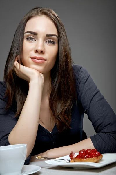 Young woman eating strawberry cake and drinking coffee — Stock Photo, Image