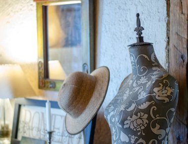 Maniqui yanında bir şapkayla süslenmiş.