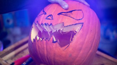 Surat asmak için Cadılar Bayramı balkabağı kesen kız