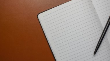 Boş kağıtların düz düzeni, not defterleri, hesap makinesi ve kahverengi deri arka plandaki kalem. Ofis masası çalışma alanı. İş, iş planı. Düz yatış, üst görünüm.