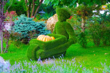 Çimenden yapılmış arabası olan bir figür.