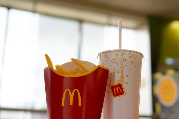 09.15.2021 tarihinde Yekaterinburg 'da çekildi. McDonalds bir kutuda patates kızartması ve hafif arka planda markalı bir bardakta içki..