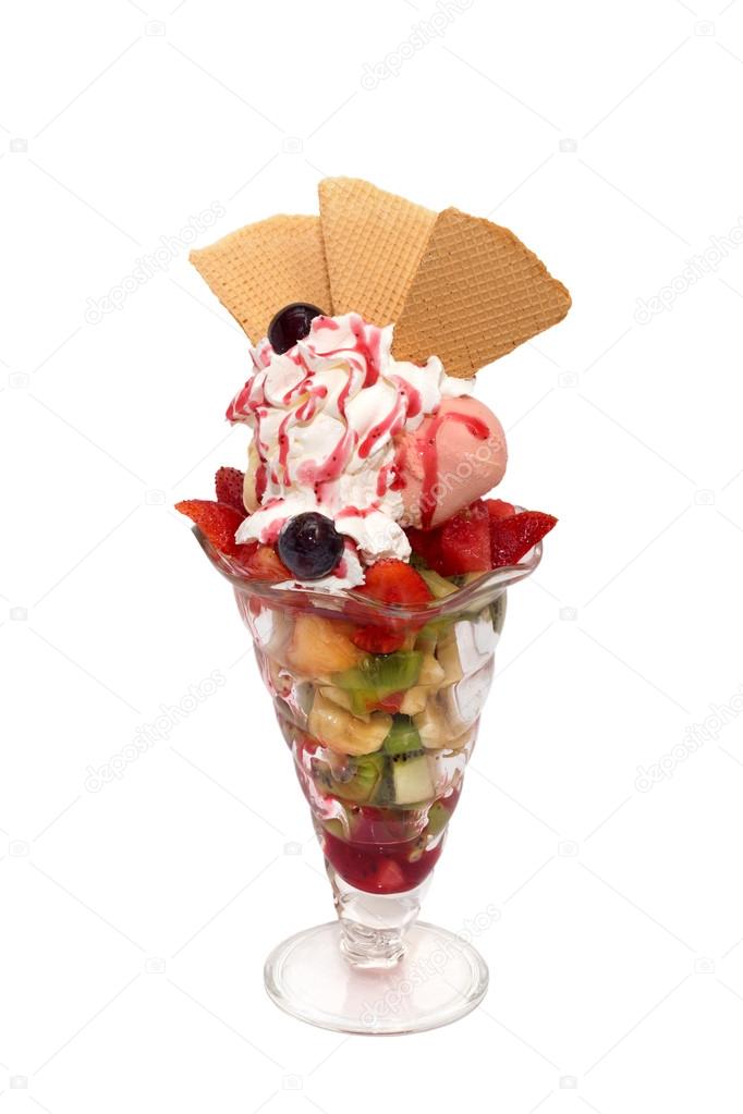 Fruit salad with ice cream, cream, topping and cookies isolated